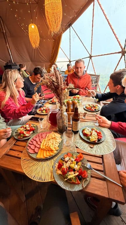 Group of people dining together at a table filled with various dishes in a unique setting.
